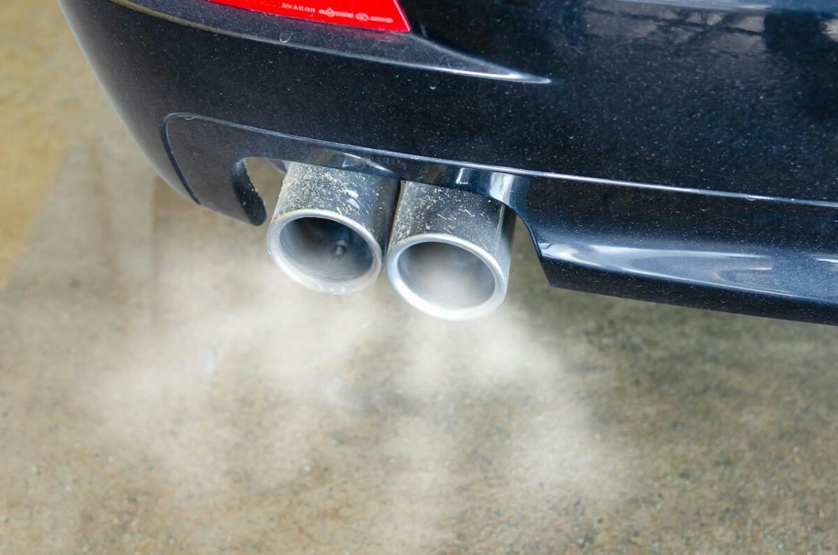 The tailpipe of a car with smoke coming out of it